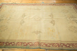Distressed Indo Chinese rug corner with time-softened ivory field and pale wine border.