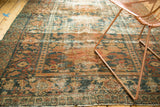 Distressed Persian Hamadan rug texture revealing worn teal, peach, and apricot tones.