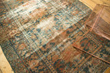 Distressed Hamadan carpet with worn pile, revealing muted teal and apricot scrolling patterns.