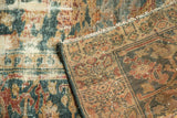 Distressed teal, blush, and ivory pile with wear, revealing the patterned hand-knotted foundation.