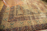 Distressed antique Kerman rug featuring faded mil fleur motifs and intricate trefoil borders.