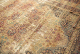 Distressed Antique Kerman carpet's mil fluer motif with trefoil design in rich red, teal, and ivory.