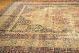 Distressed Antique Kerman carpet, displaying its ivory field, mil fleur motifs, and uniform pile wear.