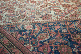 Antique Persian Mahal carpet: navy blue border with blush and gold floral motifs, low pile.