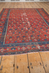 Rust red vintage Malayer rug's repeating paisley boteh with distressed pile and indigo border.