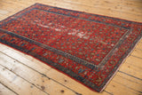 Close-up of vintage Malayer rug border, indigo geometric designs, and distressed red field.
