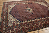 Vintage Malayer rug corner showing intricate geometric and floral borders, with blush and navy fish motif.