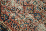 Distressed blush rose terra cotta field with blue Herati motifs and visible foundation.