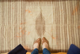 Ivory and brown striped Vintage Kurdish rug with central diamond, visible seam, faded tangerine marks.