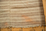Kurdish rug's fringed edge, showing vertical seam, primitive banded stripes, and orange migration.