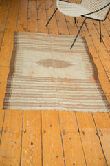 Fringed end of vintage Kurdish rug with primitive brown stripes and faded tangerine spots.