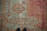 Textured close-up of a vintage Oushak rug with etched pile in blush and sea foam green.