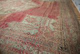 Low angle view of the etched, low pile texture of a vintage Oushak carpet in blush and sea foam green.