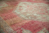 Angled view of a vintage Oushak carpet showing the etched pile and time-softened blush and seafoam colors.