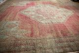 Sweeping angled view of the vintage Oushak's etched wool pile in soft blush and sea foam green tones.