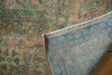 Folded view of the antique Kerman's blush and green floral pile, showing its hand-knotted foundation.