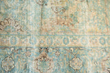 Vintage Kerman carpet with intricate floral sections, seafoam green, ivory, beige, and visible foundation wear.