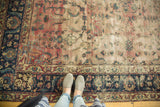 Antique Yazd carpet displays faded cranberry field, indigo floral border, and visible patch.