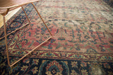 Traditional antique Yazd carpet's indigo border and faded cranberry floral vinery detail.