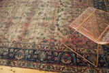 Persian Yazd rug corner with potted plants, indigo floral border, and faded cranberry field.