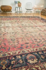 Antique Yazd rug's dark indigo border, floral vinery, and etched faded cranberry field.