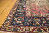 Antique Persian Yazd carpet corner detail with aged texture, indigo border, and floral vinery.