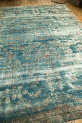 Antique Kerman rug's worn teal pile revealing faded floral patterns and detailed border.