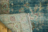 Antique Kerman carpet's worn teal pile revealing foundation and pastel patterned woven backing.
