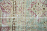 Vintage Malayer carpet close-up with faded blush, sea foam green floral motifs and visible foundation.