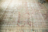 Faded and worn field of vintage Malayer carpet with blush, green, and ivory floral patterns.