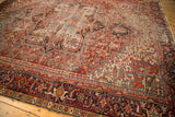 Vintage Heriz carpet detail: brick red, navy geometric patterns, short pile, visible wear.