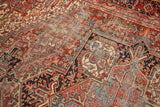 Rectilinear geometric floral pattern with visible knot heads and worn pile on a vintage Heriz rug.