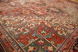 Rectilinear geometric floral pattern and serrated leaves on vintage Heriz carpet, brick red, blue, and beige.