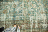 Vintage Kerman rug with worn pile, visible foundation. Muted blue, red, ivory floral patterns.