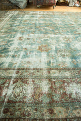 Distressed sky blue Kerman carpet with vine motifs, showing foundation and a mended seam.