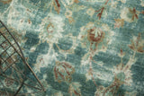 Vintage Kerman carpet close-up: time-softened sky blue, cochineal palmettes, with foundation wear.
