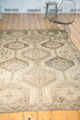 Vintage Qashqai rug's geometric border, time-softened ivory field, and short fringe.