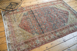 Distressed corner of antique Malayer rug, with faded saffron and teal Herati pattern.