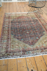 Antique Malayer rug's lower border, white fringe, and distressed Herati motif in brick red and teal.