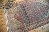 Antique Malayer rug's fringe and geometric border pattern in brick red and ivory with distress.