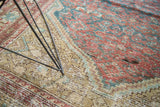 Faded brick red, teal, and saffron Herati patterns on the antique Malayer rug's textured pile.