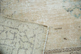 Folded corner of vintage Tabriz rug showing worn antique ivory pile and hand-knotted charcoal reverse.