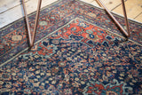 Intricate henna plant motifs on vintage Farahan Sarouk rug in madder red and navy.