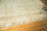 Vintage Kerman carpet's muted ivory field with scrolling tendrils and soft green vinery.