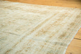 Edge of vintage Kerman carpet showing mostly even wear, muted ivory and seafoam green floral patterns.