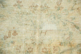 Vintage Kerman carpet detail showing mostly even wear, exposed foundation, and faint floral patterns.