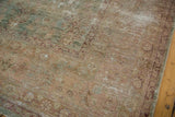 Antique Kerman carpet's distressed pile, exposed foundation, and faded blush, sea foam motifs.