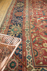 Intricate scrolling vinery and lotus flowers on a cherry red and navy antique Mahal rug.