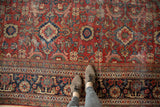 Vintage Mahal rug featuring allover cherry red palmettes, navy blue arabesques, and visible textured wear.