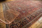 Vintage Persian Mahal carpet: cherry red field and navy border with traditional palmette arabesques.